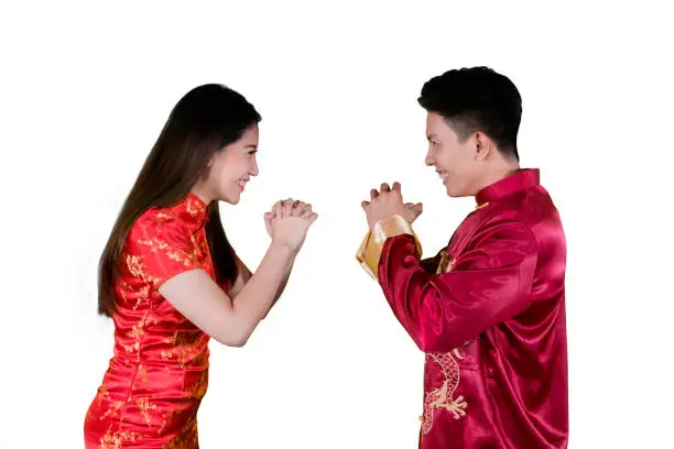 Image of young couple wearing traditional Chinese dress while giving gong xi fa chai greetings in the studio