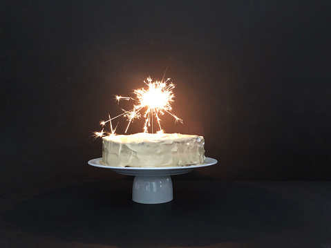 Whole layer carrot cake with sparkler on black background
