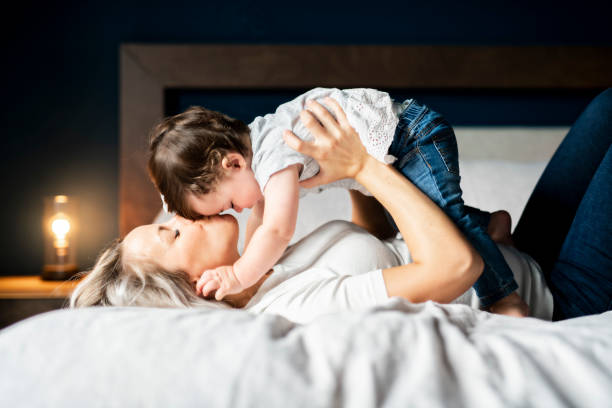 mère de jouer avec la fille de bébé dans la chambre à la maison - single mother one parent child kissing photos et images de collection