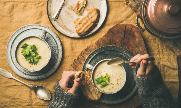 zupa z kremu selera w kubkach i kobiece ręce z łyżką - hot lunch zdjęcia i obrazy z banku zdjęć