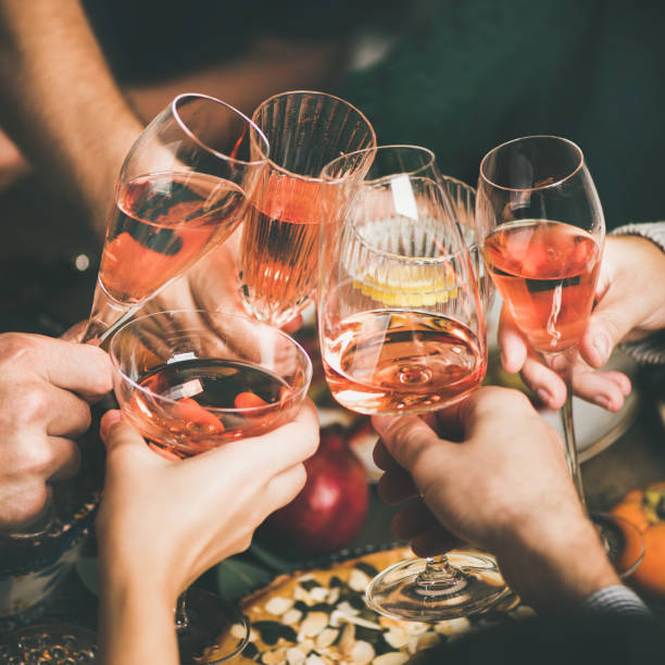Friends clinking glasses with rose wine at Christmas, square crop