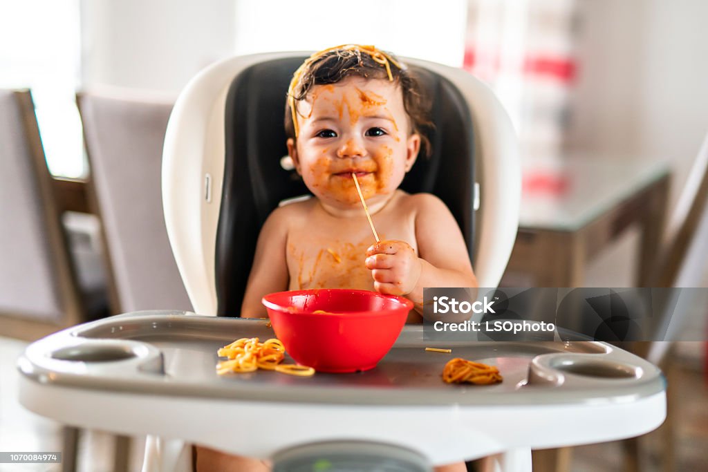 child girl, eating spaghetti for lunch and making a mess at home in kitchen A child girl, eating spaghetti for lunch and making a mess at home in kitchen Baby - Human Age Stock Photo