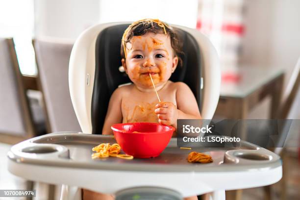 Child Girl Eating Spaghetti For Lunch And Making A Mess At Home In Kitchen Stock Photo - Download Image Now