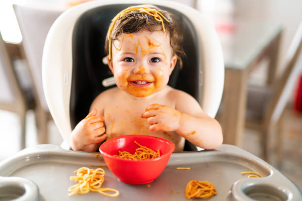 istock child girl, eating spaghetti for lunch and making a mess at home in kitchen 1070085268