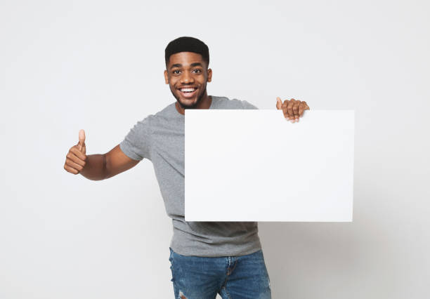 hombre afroamericano holding pizarra en blanco y mostrando el pulgar hacia arriba - man holding a sign fotografías e imágenes de stock