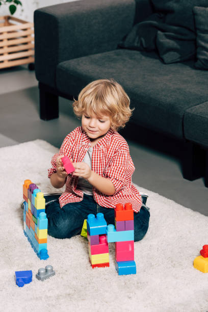 istock curly little boy playing with colorful plastic blocks on floor at home 1070089862