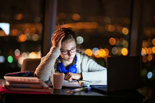 Teenage girl doing homework and studying late at night
Nikon D850