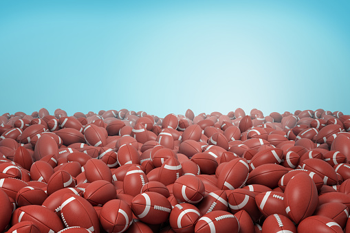 3d rendering of endless heap of identical red leather balls for American football on blue background. Traditional sport. Team game. Equipment and gear for sport.