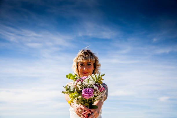 istock Bride poses with her bouquet under a blue sky 1070095724