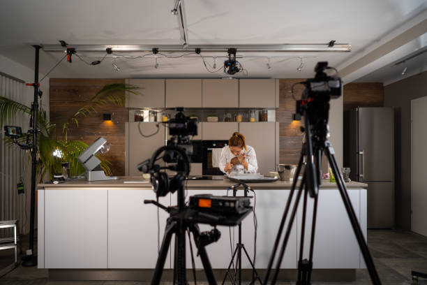 tv set studio kitchen female cook preparing cookies food vlogger v-logger blogger influencer woman recording video vlog vlogging in tv-show studio kitchen for social media behind the scenes film and audio equipment visible behind the scenes photos stock pictures, royalty-free photos & images