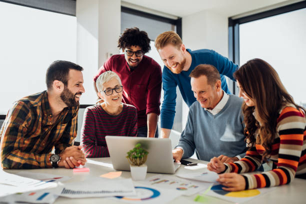 istock Old businessman using laptop with coworkers 1070121122