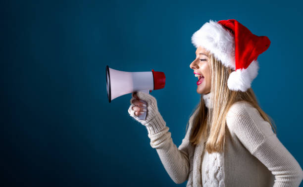 istock Young woman with santa hat holding a megaphone 1070125726