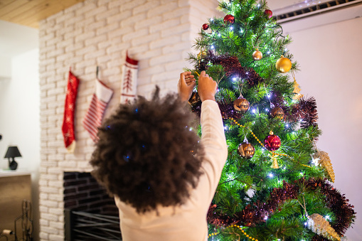 Unrecognizable  little girl decorating Christmas  tree