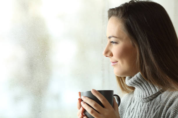 비 창을 통해 커피를 들고 찾고 행복 한 여자 - window rain winter house 뉴스 사진 이미지