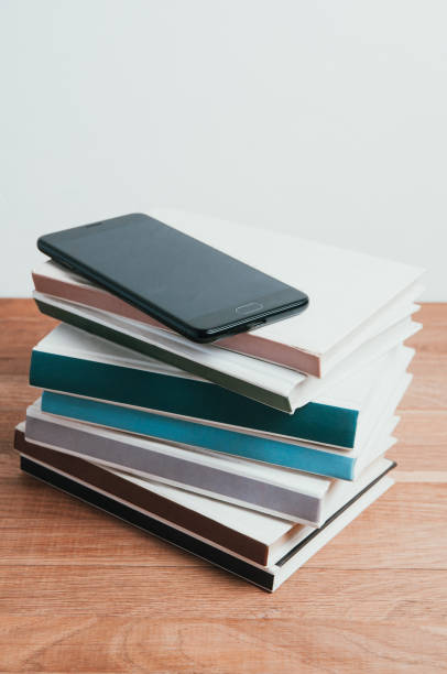 istock Black smartphone and a stack of books on a light background 1070128634