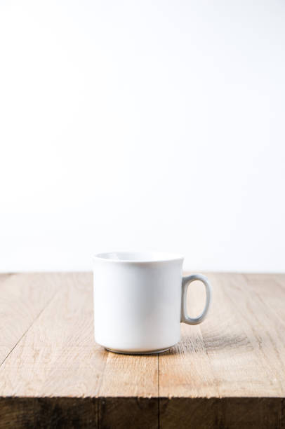 istock White mug on a wooden table. Template for text or design 1070129686