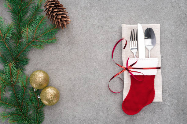 istock flat lay with fork, spoon with knife in santa sock wrapped by red ribbon on table with pine cone and branch decorated by golden christmas balls 1070133078