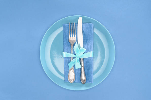 istock flat lay with fork and knife wrapped by festive ribbon on plate isolated on blue 1070133548