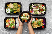 Plastic containers with delicious food on gray background