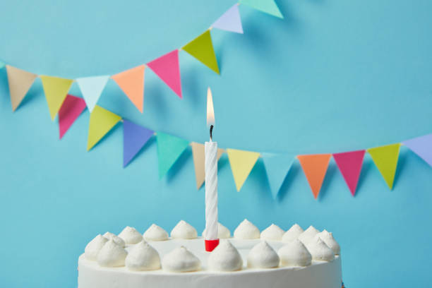istock Candle on delicious birthday cake on blue background with bunting 1070141946