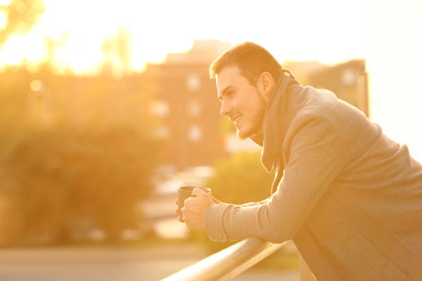 istock Happy man drinking coffee looking away from a balcony 1070142046