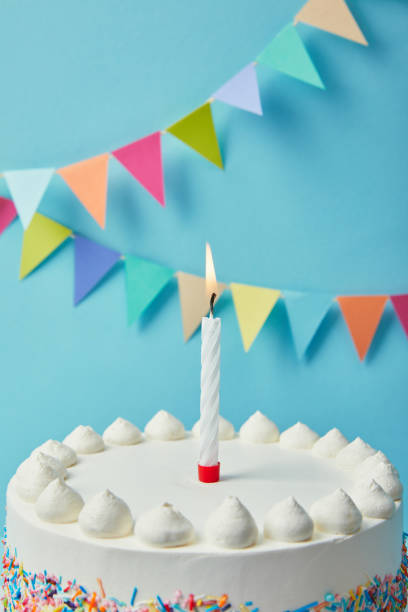 istock Candle on tasty birthday cake on blue background with bunting 1070142682
