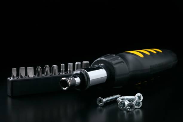 istock Screwdriver with bitset and tapping screw on black background 1070147050