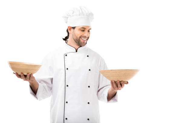 istock happy young chef holding bowls isolated on white 1070151500