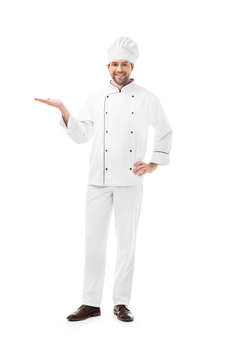 full length view of young chef showing copy space and smiling at camera isolated on white
