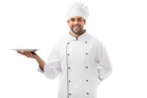 istock smiling young chef holding empty plate and looking at camera isolated on white 1070153562