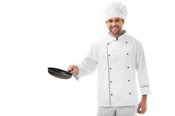 istock smiling young chef holding frying pan and looking at camera isolated on white 1070153676