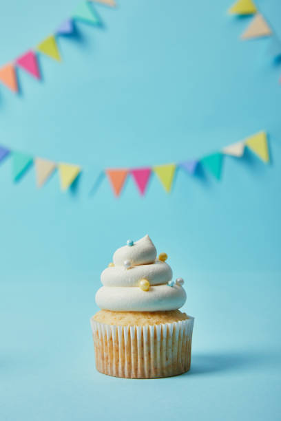 istock Delicious cupcake with sugar sprinkles on blue background with bunting 1070158934