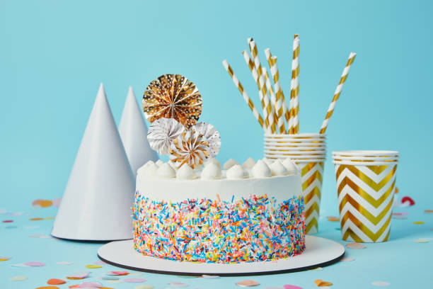 istock Delicious cake, plactic cups, party hats and drinking straws on blue background with confetti 1070159240