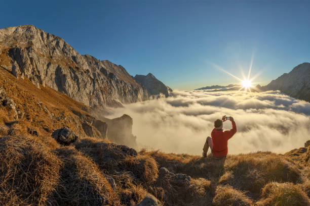 alpiniste prendre photo avec le téléphone mobile au lever du soleil - alpes - salzkammergut photos et images de collection