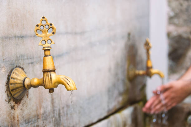 due vecchi rubinetti pubblici a istanbul, in turchia. acqua che scorre e persona che lava le mani sullo sfondo. - istanbul people faucet turkey foto e immagini stock