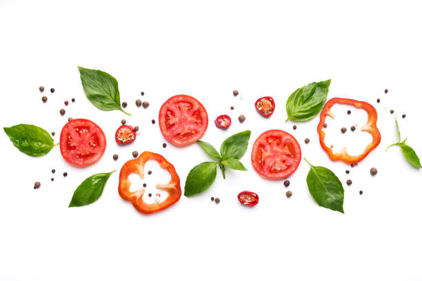 Composition of vegetables, herbs and spices on white background Food art. Creative composition of cut pepper, tomato, basil leaves and spices on white background, top view basil photos stock pictures, royalty-free photos & images