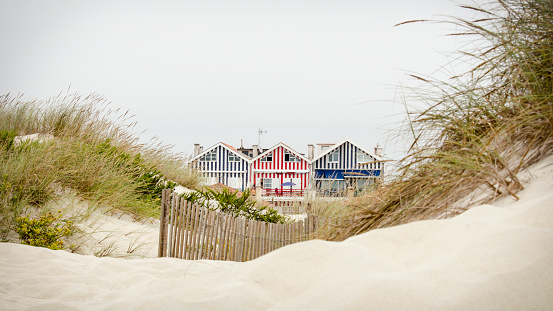 Horizontal photo of idyllic and quaint beach houses seen from beach dunes. Beach houses with colorful stripes from Costa Nova, Portugal.