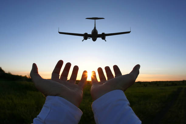 istock raised hands on the background of a passenger plane flying at sunset 1070179528