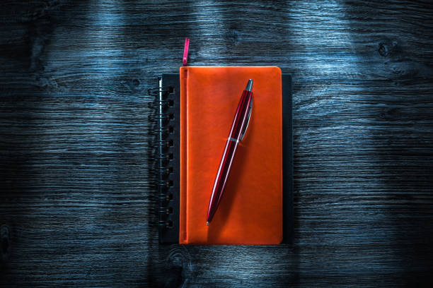 istock Notebooks pen on vintage wooden board top view 1070179536