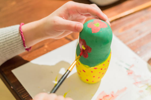 istock Kid decorating wooden doll toy (russian matrioshka) at the workshop 1070184870