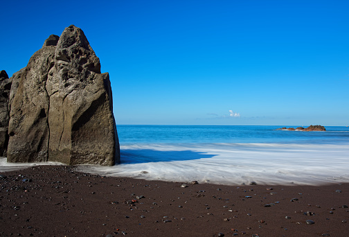Rock formation on Praia Formosa beach - famous public black sand beach on Portuguese island of Madeira
