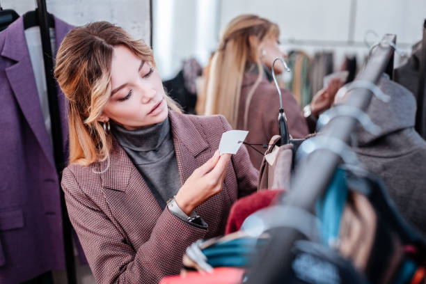 Elegant businesswoman shopping on weekend checking the price of dress Check price. Elegant fashionable businesswoman shopping on weekend checking the price of dress price tag photos stock pictures, royalty-free photos & images