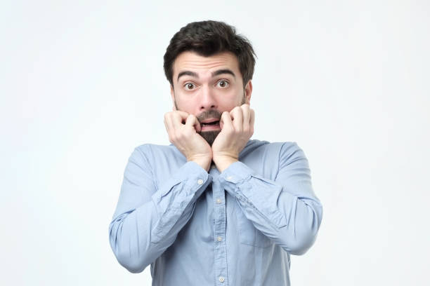 istock Young man dressed in casual clothes, biting nails and rounding eyes 1070194560