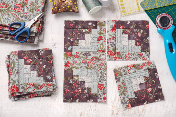 istock Patchwork log cabin blocks, stack of blocks, sewing accessories on white wooden surface 1070196644