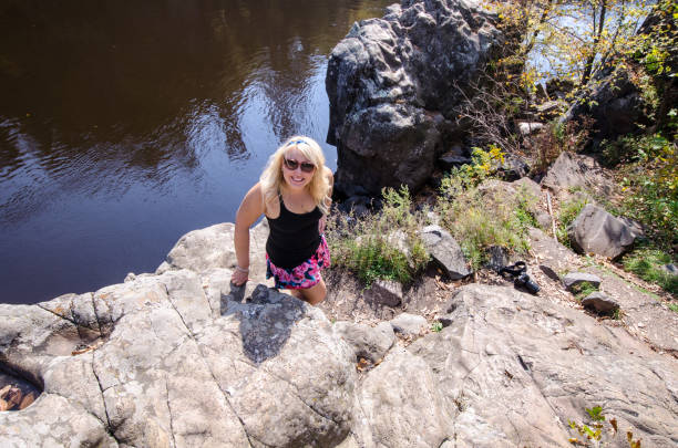 Blonde female hiker stands on a bluff cliff at Interstate State Park