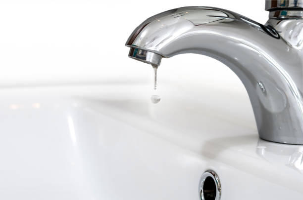 bateria z kroplą wody przed białym zlewem. wyciek i oszczędność wody - leaking faucet water scarcity zdjęcia i obrazy z banku zdjęć