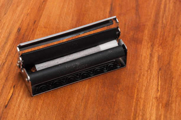 istock Hand rolled cigarette in the machine on the wooden background 1070201402