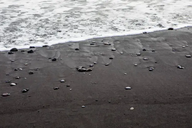 A view of the black sand and pebbles on Reynisfjara Beach, near the fishing village of Vik on the south coast of Iceland.