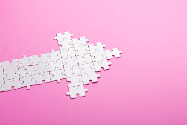 White puzzle. Arrow shape puzzle on pink background. Top view stock photo