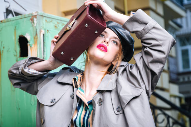 istock Red-haired slim photo model with red lips holding little leather bag 1070216730